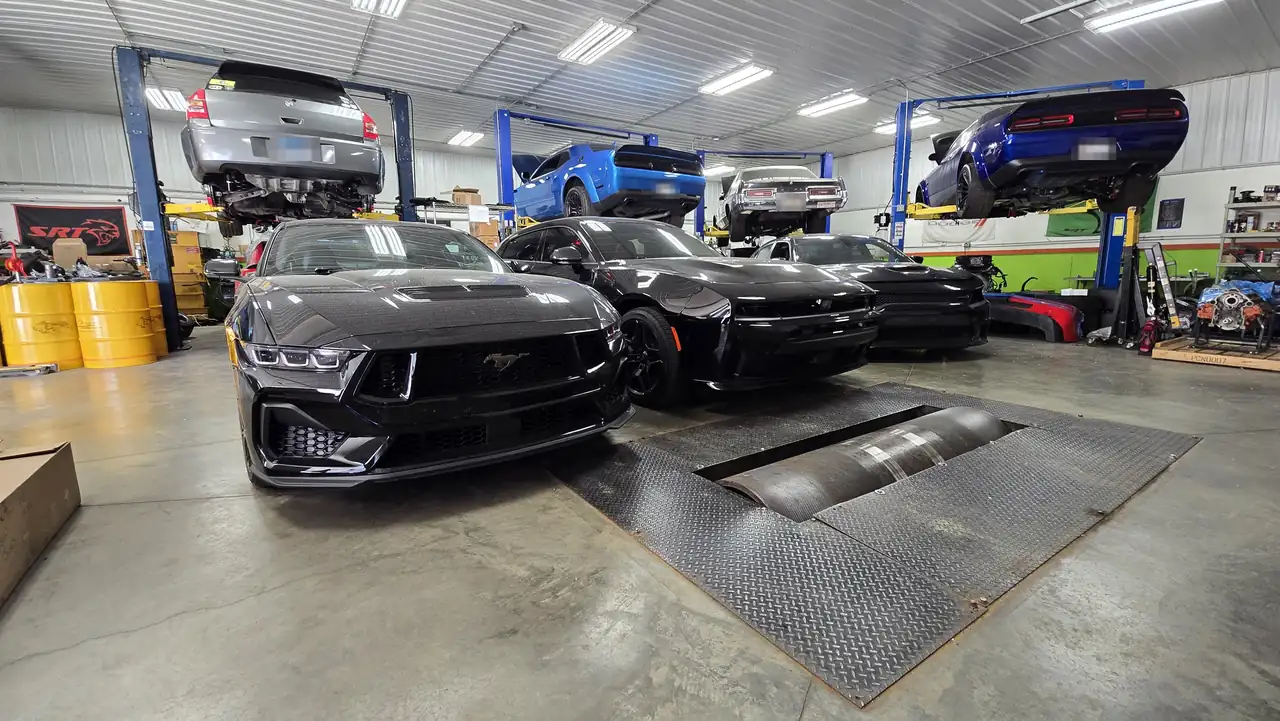 Black 2024+ Ford Mustang beside the in-ground chassis dyno rollers at Satera Tuning