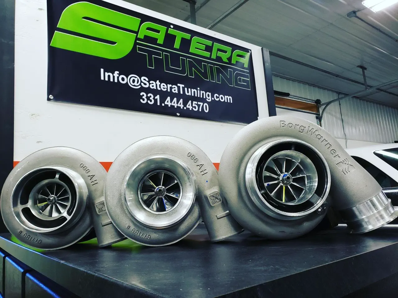 Three turbochargers in front of a Satera Tuning banner
