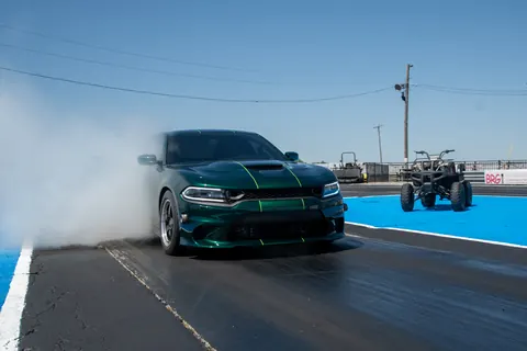 Side view of the green Satera Tuning Charger Hellcat shop car with neon-green stripes doing a burnout